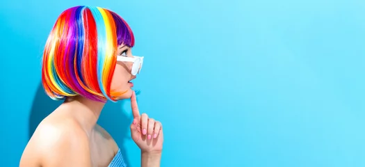 Foto op Plexiglas Beautiful woman in a colorful wig on a blue background © Tierney
