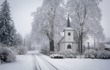 White chapel under snowy trees in a small village in winter