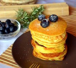 Stack of sweet homemade pancakes with fresh blueberries on a plate.