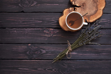A cup of hot tea and lavender on a dark wooden background top view. Herbal tea Hot drink Mood Lavender