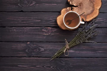 Papier Peint photo Theé A cup of hot tea and lavender on a dark wooden background top view. Herbal tea Hot drink Mood Lavender