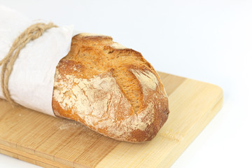 Fresh French baguette in paper wrap on wood board with white background