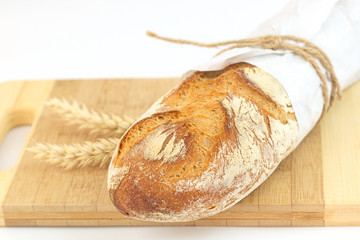 Fresh French baguette in paper wrap on wood board with white background