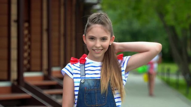 The girl in a striped t-shirt poses for the camera in the park
