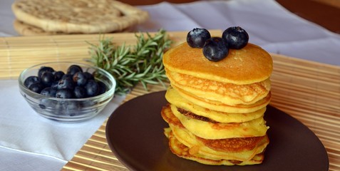 Stack of sweet homemade pancakes with fresh blueberries on a plate.