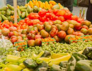 Farmer's market produce for sale at stand. Color horizontal photo of heirloom tomatoes, cherry tomatoes, brussel sprouts, zucchini, squashes, gypsy peppers and bell peppers are visible.