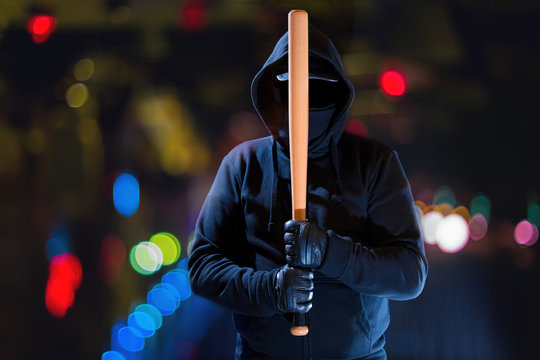 ein mit einem Baseballschläger bewaffneter, extremer Demonstrant in einer Stadt bei Nacht