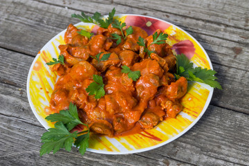Chicken gizzard stew in plate on rustic wooden table