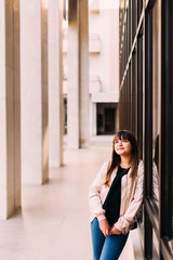 Nice girl standing at the modern building and looking up. Column