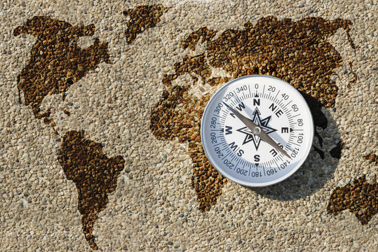 Compass and world map on small gravel stone, Find the right way for our earth concept
