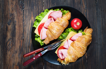 Light and hearty spring breakfast. Croissant with ham, cheese, fresh tomatoes on a wood stone table