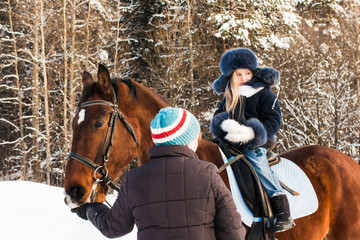 Obraz premium Small girl, horse trainer and horse in a winter