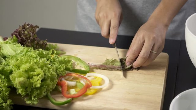 Woman cutting fresh salad vegetable for making salad. UHD 4k 3840x2160.
