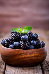 Blackberry and Blueberry with Mint. Fresh Berry in a wooden bowl on a wooden Vintage Background.Food or Healthy diet concept.Vegetarian.Copy space for Text.selective focus