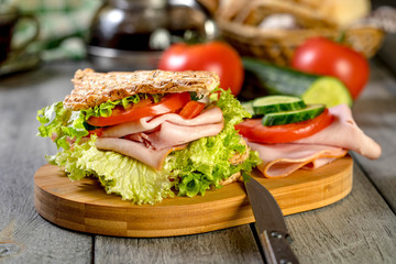 Sandwich with ham, cucumber, tomato and lettuce.