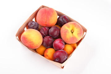 Peaches, apricots and plums in a basket isolated on white background