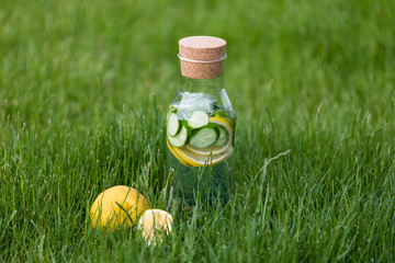 A glass decanter with a summer refreshing lemonade made of lemons and cucumber with mint added on a...