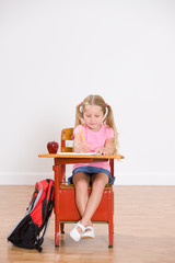 School: Little Girl Student Sits At Desk Doing Homework