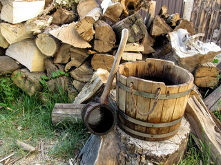 A wooden rural vintage bucket and a ladle on the background of a pile of firewood. Beautiful photo...