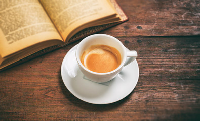 Vintage book and a cup of coffee on wooden background
