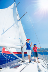 Boy with his sister on board of sailing yacht on summer cruise. Travel adventure, yachting with child on family vacation.