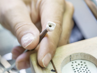Closeup of dental technician applying ceramic to teeth, implant before putting into the furnace