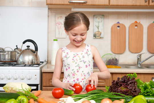 Child girl having fun with tomatoes. Home kitchen interior with fruits and vegetables. Healthy food concept