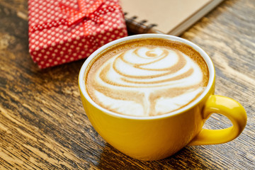 Latte cup on wood. Rose coffee foam art.