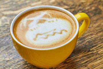 Island latte art. Yellow cup with coffee beverage.