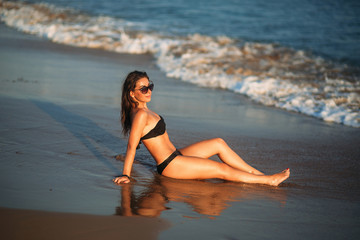 Fototapeta na wymiar Beautiful girl sunbathing on a sandy beach. sunset silhouette 