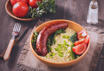 Traditional Dutch dish Stamppot. Mashed potatoes, curly kale with fried bacon and rookworst on rustic table