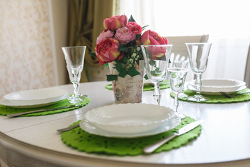 Bouquet of pink peonies flowers on a table with cutlery