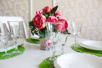 Bouquet of pink peonies flowers on a table with cutlery