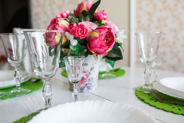 Bouquet of pink peonies flowers on a table with cutlery
