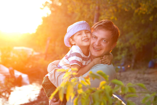 happy father and son playing on river at the sunset time. Concept of friendly family.