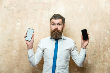 hipster or bearded man compare mobile phone and smartphone