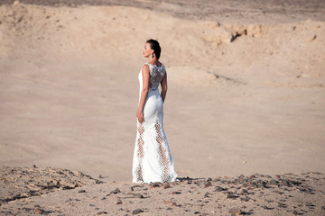 Fototapeta na wymiar Bride young pretty woman brunette posing back on desert background