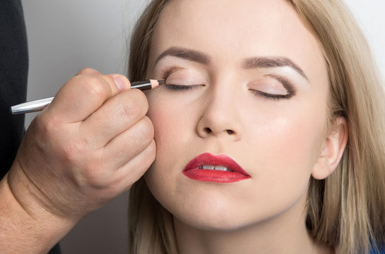 Girl with closed eyes getting makeup on eyelids