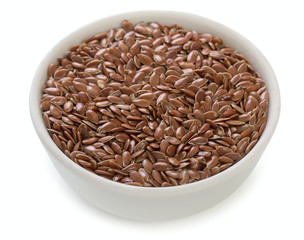 Little bowl of dried flax seeds isolated on white background, close up.