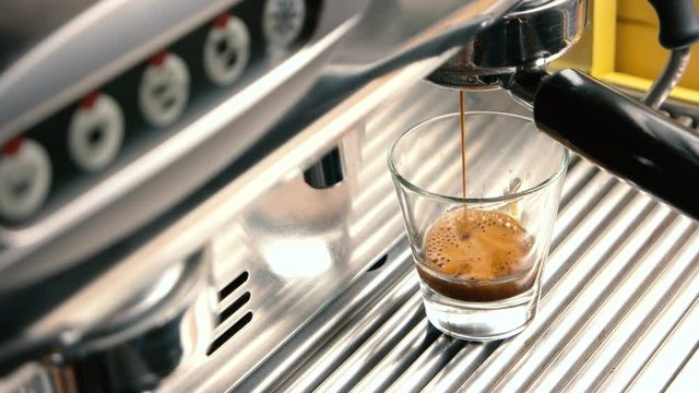 Espresso machine and shot glass. Fresh coffee with foam.
