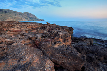 Fototapeta na wymiar Beautiful mysterious marine landscape at sunset. Volcanic reef and ocean
