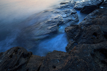 Beautiful mysterious marine landscape at sunset. Volcanic reef and ocean