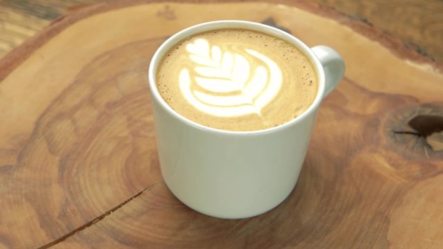 Close up of latte cup. Coffee beverage on wooden board.