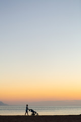 Obraz premium Silhouette of mother with stroller enjoying motherhood at sunset landscape