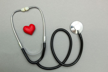 Medical stethoscope and red heart isolated on a gray background. Top view.