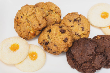 Top view of a plate of oatmeal chocolate, shortbread cookies on a white background