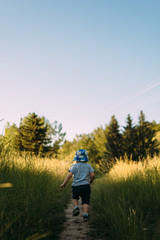 Naklejka na ściany i meble Toddler running through a field in summer