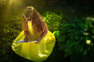 A girl in a yellow dress sits on the grass and draws