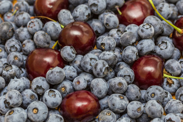 Natural bright background of natural fresh ripe blueberries and cherries close-up