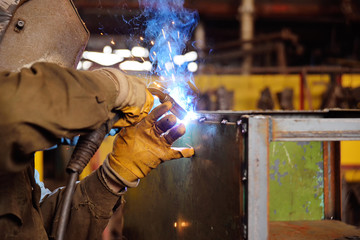 Welder for his work. Welding sparks on production background